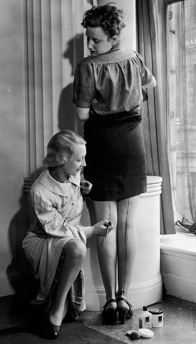 Mujer pintando la raya de una media Mujer pintando la raya posterior de una media